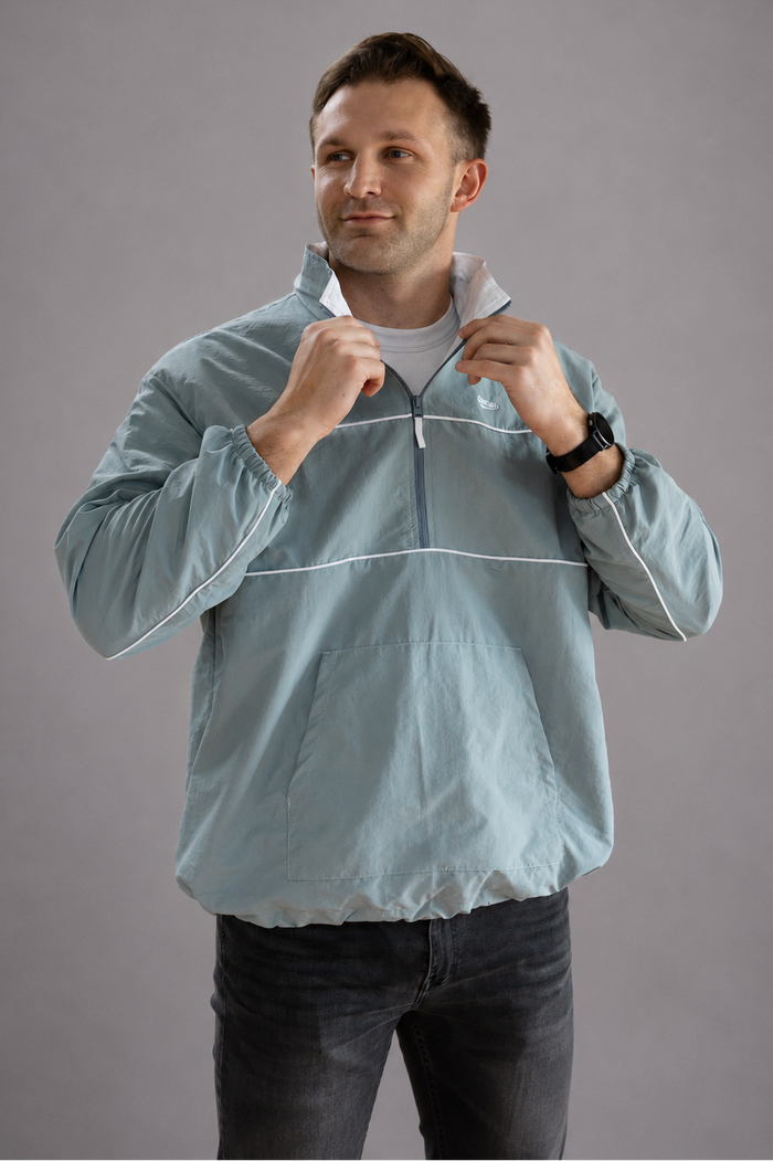 Man wearing a light blue jacket against a gray background