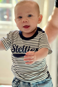 Baby wearing a striped shirt with 'Stellies' on it.