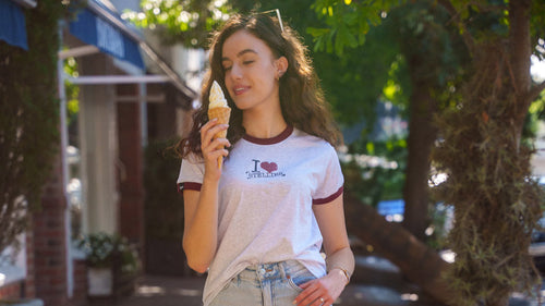 Woman walking on a sidewalk holding an ice cream cone, wearing a casual outfit.